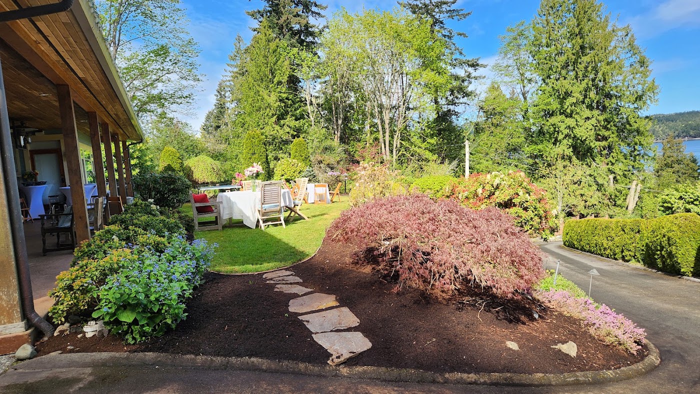 Stepping stones beside a Japanese maple, planted beds and a green lawn